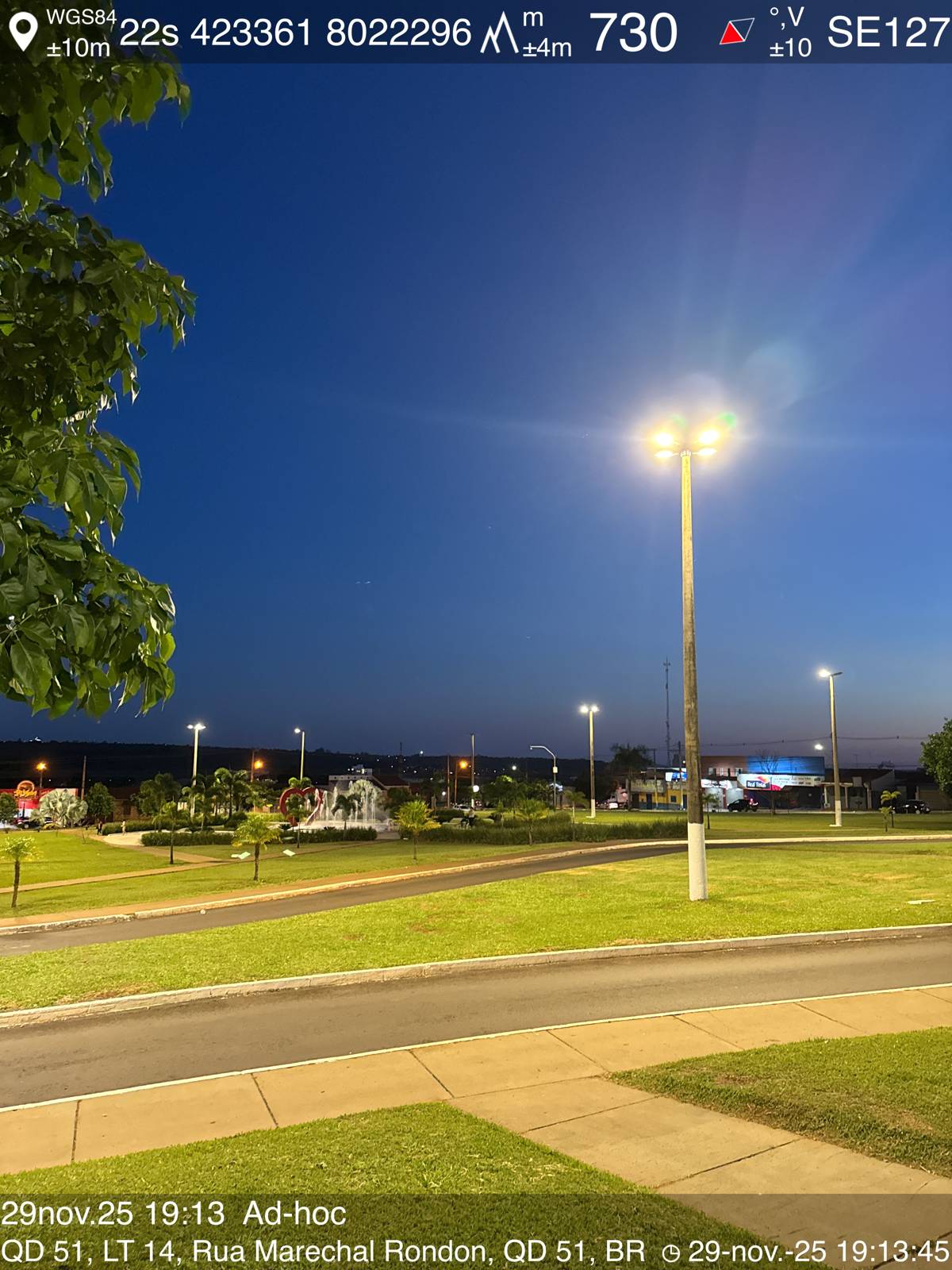 Registro de medição luminotécnica em campo, com dados de GPS sobrepostos à foto de uma praça iluminada à noite